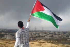 Person waving a Palestinian flag, photo by Ahmed Abu Hameeda